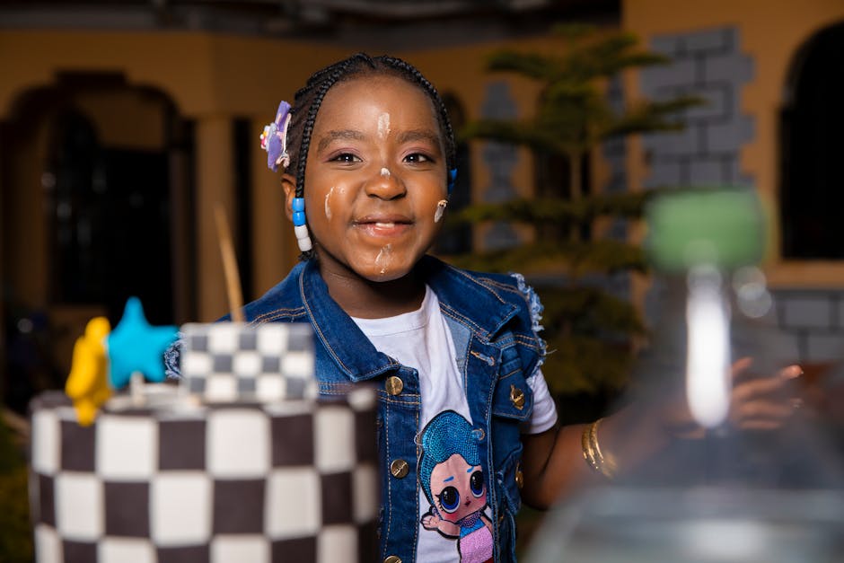 Happy child with braided hair enjoying a colorful cake celebration outdoors at night.