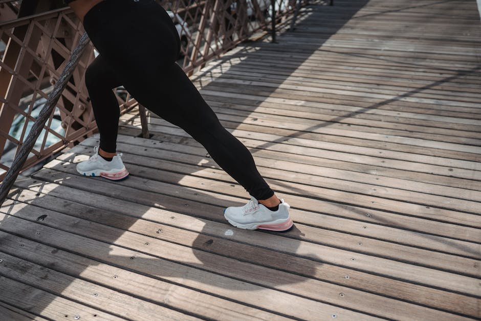 An adult woman stretching her legs on a wooden bridge in daylight, embodying a healthy lifestyle.