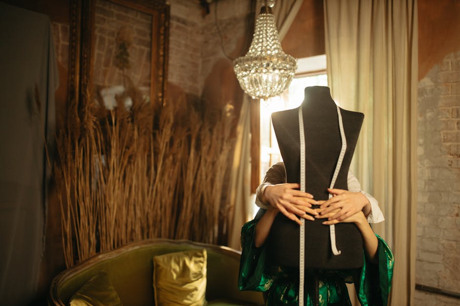 A stylish fashion workshop featuring a mannequin, vintage sofa, and ornate chandelier, creating a cozy atmosphere.