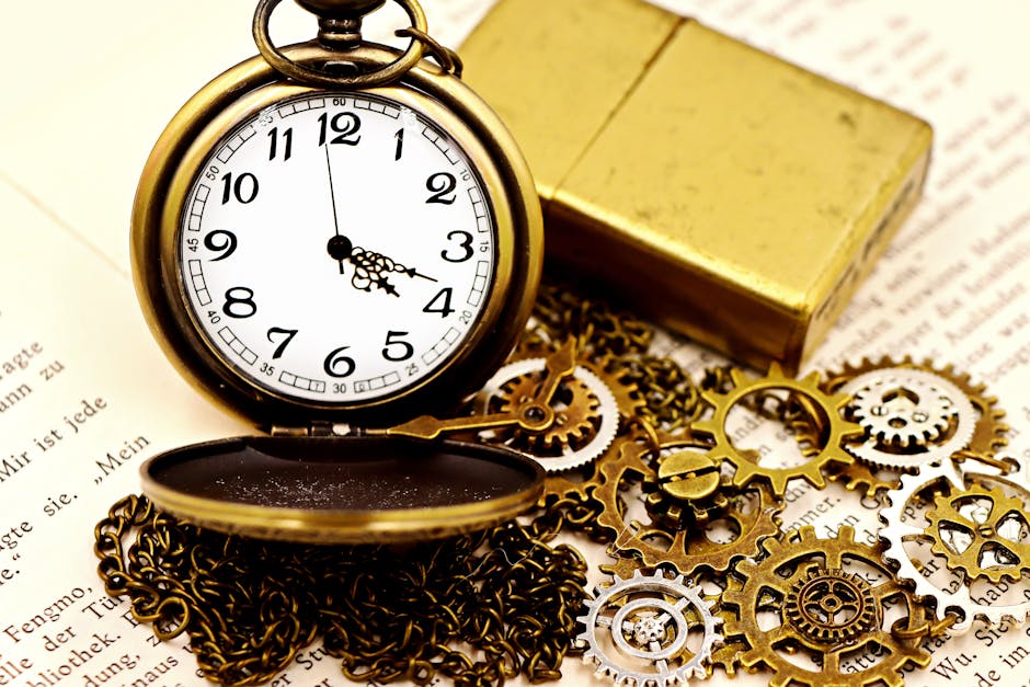 Close-up of an antique pocket watch with gears, chain, and gold lighter on open book pages.