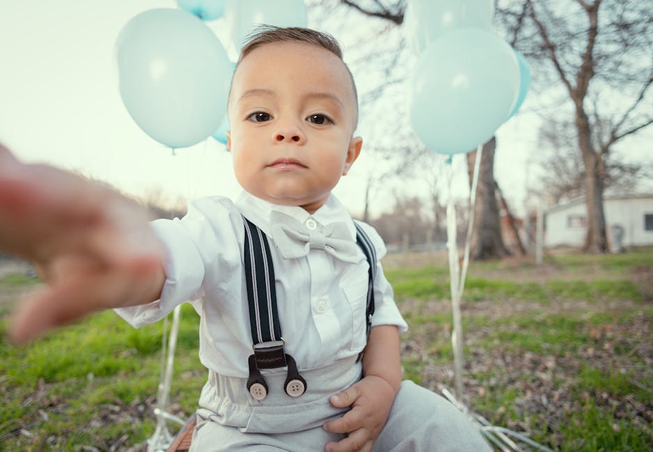 Cute toddler dressed formally with blue balloons, seated outdoors in Tulsa, Oklahoma.
