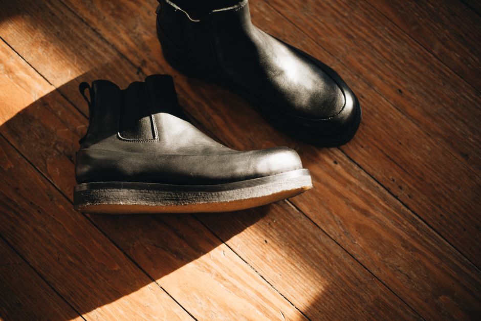 Stylish leather boots showcased on a warm wooden floor with moody lighting.