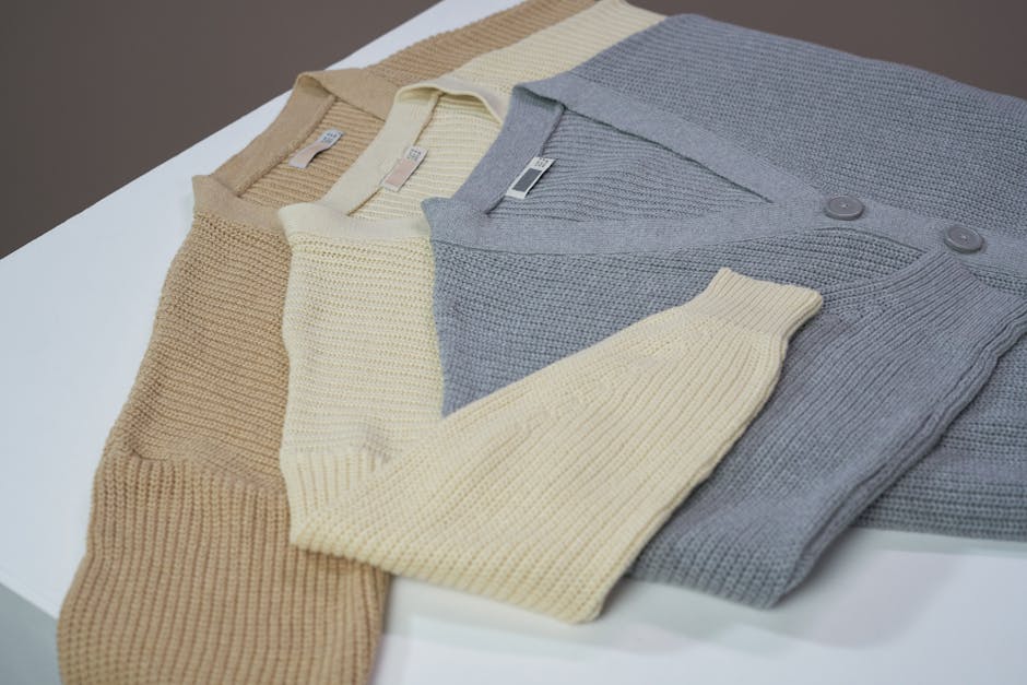 Flatlay of beige, cream, and gray cardigans on a white surface. Perfect for online shopping and fashion catalogs.