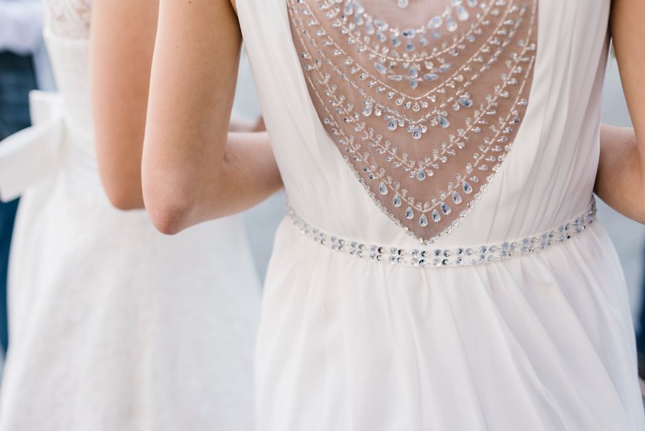 Close-up of elegant white bridal gowns adorned with intricate embellishments and jewels.